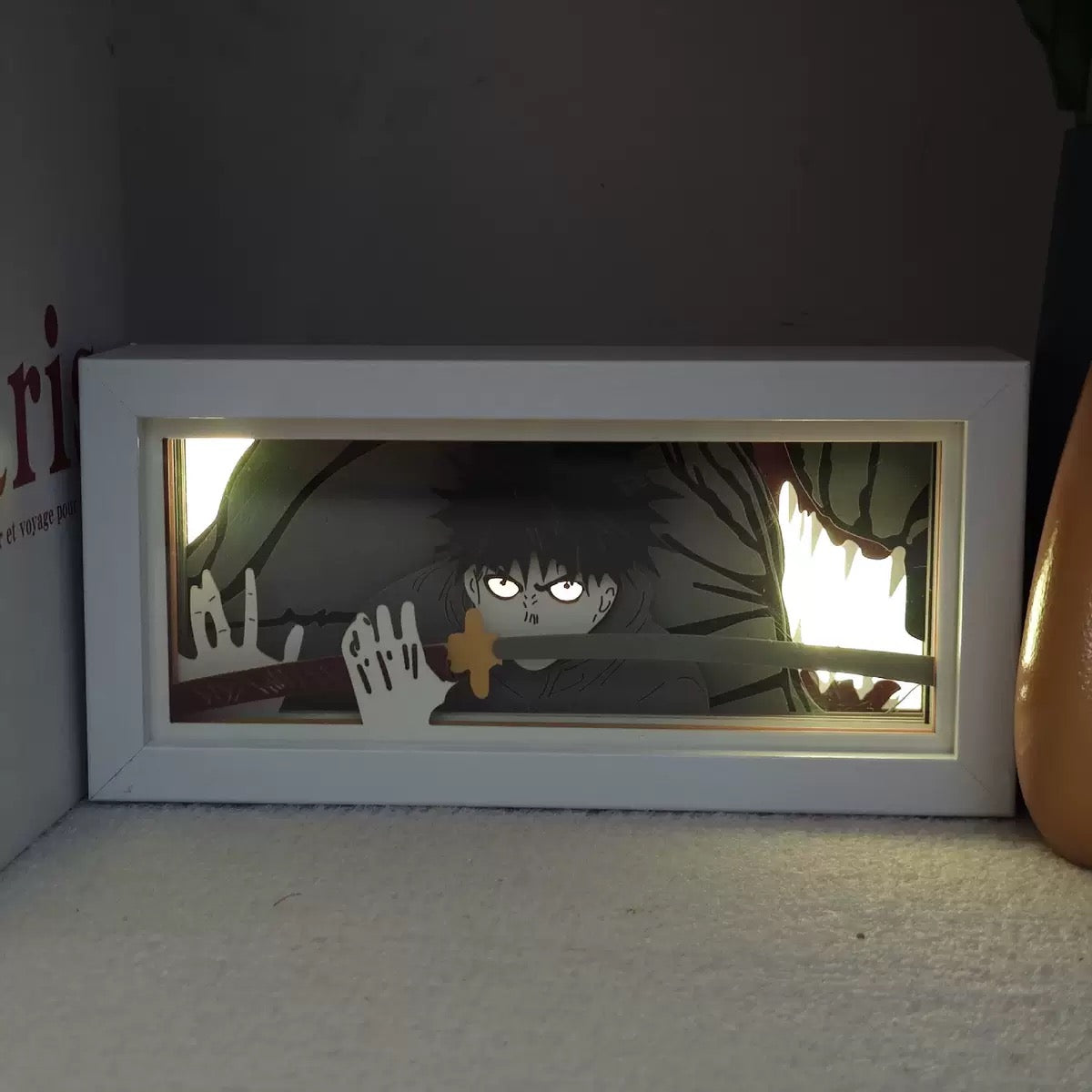 Oeuvre encadrée d'un personnage animé Megumi avec une bordure blanche sur une étagère.