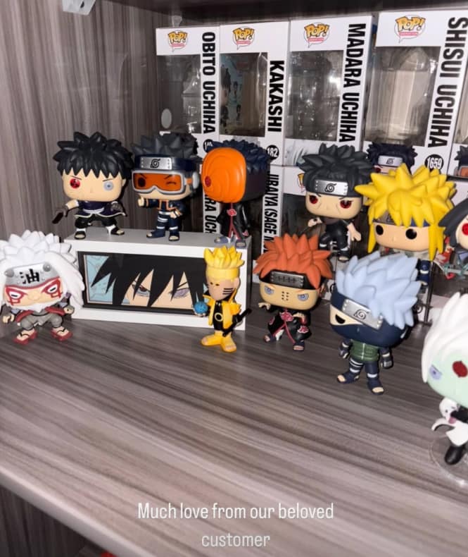 Collection of Naruto-themed figurines on a shelf featuring a Sasuke Anime Light Box in the background.