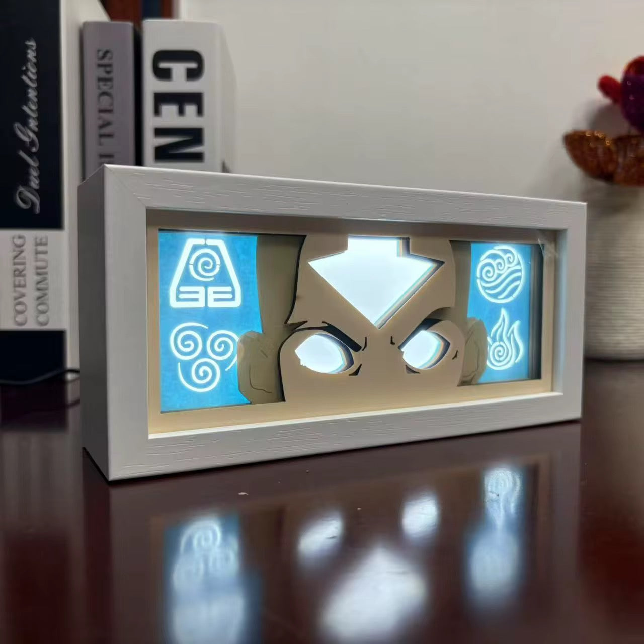 Pemandangan sampingan kotak cahaya Aang menunjukkan udara, air, bumi, dan ikon api menyala dengan warna biru

