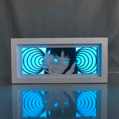 Kotak cahaya manga seram tomie dengan lampu latar biru dan spiral hipnosis

