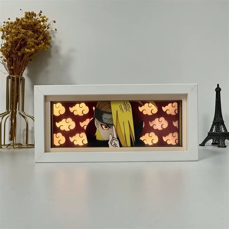LED ANIME Light Box s Deidarou z Naruto v Akatsuki Cloak s pozadím červeného cloudu, osvětleného na bílé stolní desce.