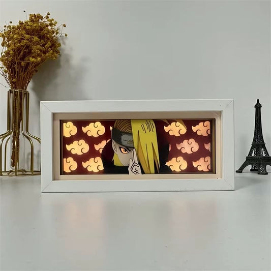 Kotak cahaya anime LED yang memaparkan Deidara dari Naruto di Akatsuki jubah dengan latar belakang awan merah, diterangi pada meja putih.